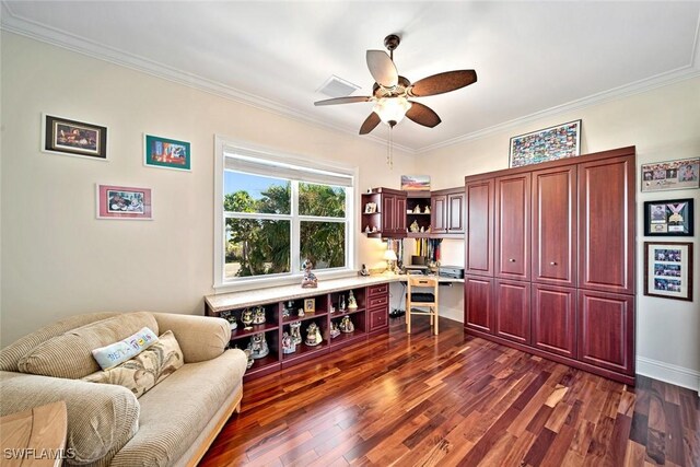 office featuring ceiling fan, built in desk, ornamental molding, and dark wood-type flooring