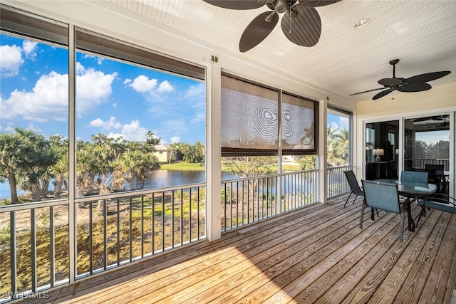 unfurnished sunroom featuring ceiling fan and a water view