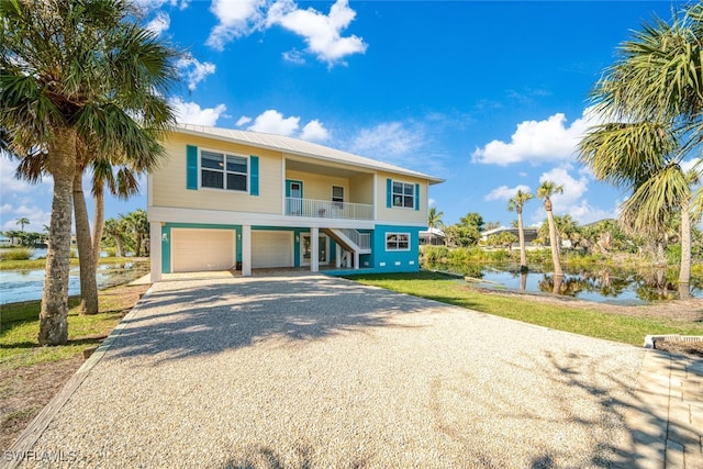 beach home featuring a front yard, a water view, and a garage