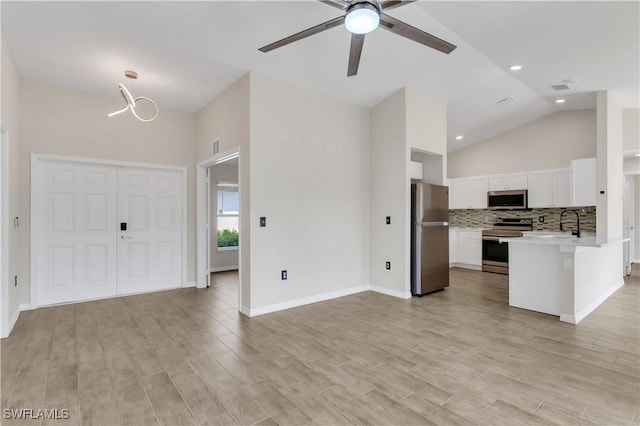 kitchen featuring appliances with stainless steel finishes, backsplash, ceiling fan with notable chandelier, light hardwood / wood-style flooring, and white cabinetry