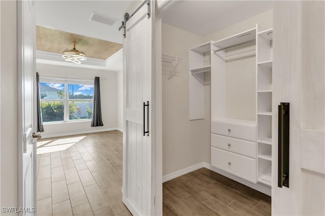 walk in closet with a barn door and light hardwood / wood-style flooring