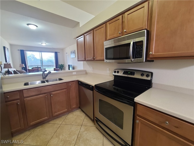 kitchen featuring kitchen peninsula, light tile patterned floors, stainless steel appliances, and sink