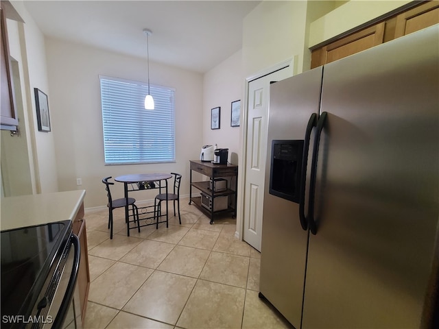 kitchen featuring black electric range, stainless steel fridge, decorative light fixtures, and light tile patterned floors