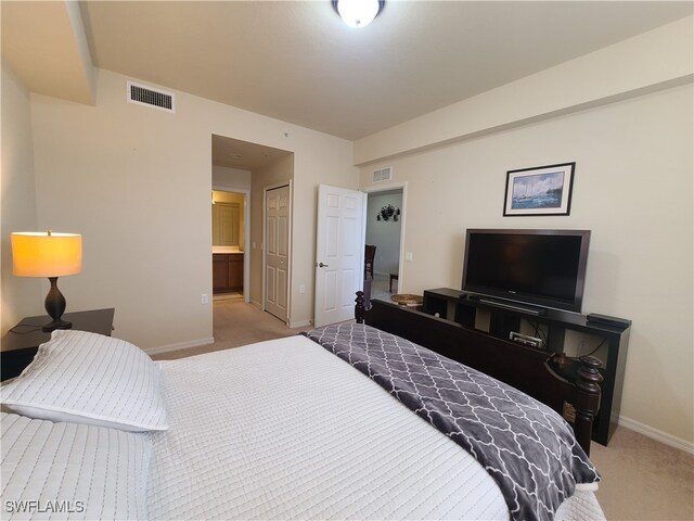 bedroom with connected bathroom and light colored carpet