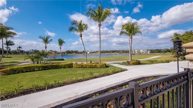 surrounding community with a water view and a yard