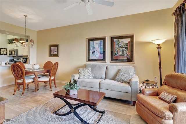 living room featuring ceiling fan with notable chandelier and light hardwood / wood-style floors