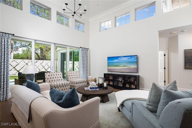 living room featuring an inviting chandelier, hardwood / wood-style floors, a towering ceiling, and ornamental molding