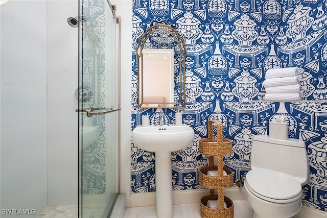 bathroom featuring a shower with door and toilet