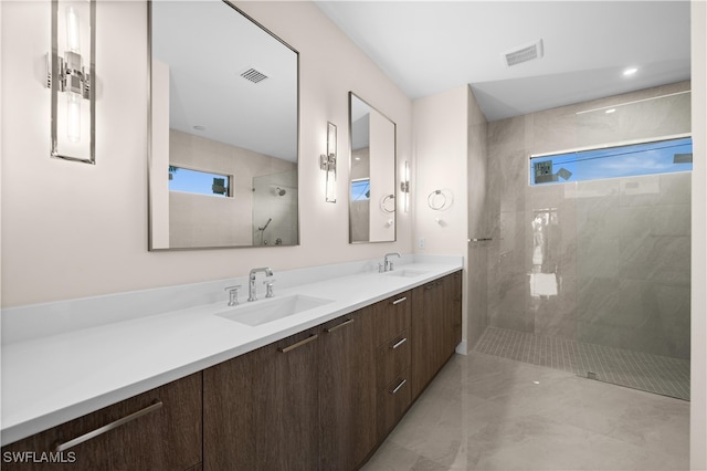 bathroom with tiled shower, vanity, and a healthy amount of sunlight