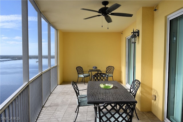 sunroom with ceiling fan and a water view