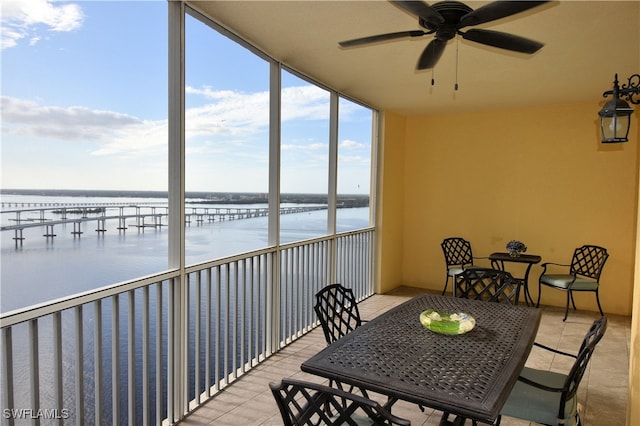 sunroom / solarium with ceiling fan and a water view