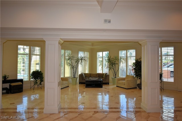 interior space featuring plenty of natural light, ornamental molding, and decorative columns