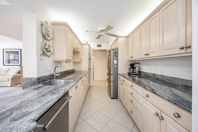 kitchen featuring appliances with stainless steel finishes, dark stone counters, ceiling fan, sink, and light tile patterned floors