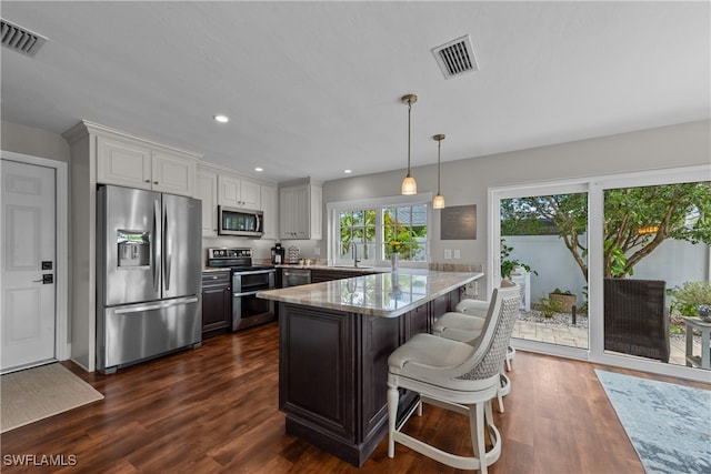 kitchen featuring pendant lighting, sink, white cabinetry, stainless steel appliances, and light stone countertops