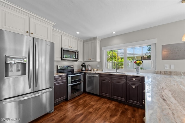 kitchen with appliances with stainless steel finishes, dark hardwood / wood-style floors, white cabinetry, sink, and dark brown cabinetry