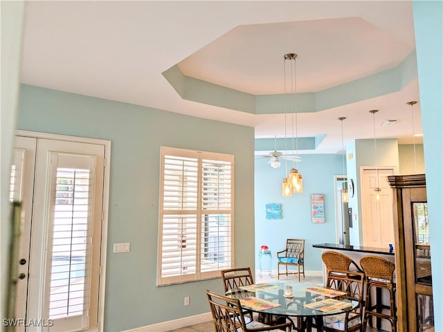 dining space featuring a tray ceiling, ceiling fan, and a healthy amount of sunlight