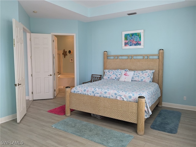 bedroom featuring ensuite bath and hardwood / wood-style flooring