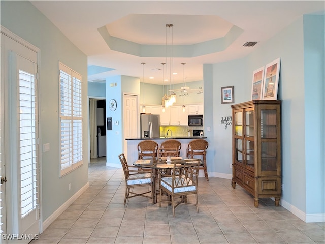 dining room with light tile patterned floors, a raised ceiling, and sink