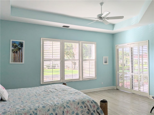 bedroom with access to outside, multiple windows, ceiling fan, and light wood-type flooring