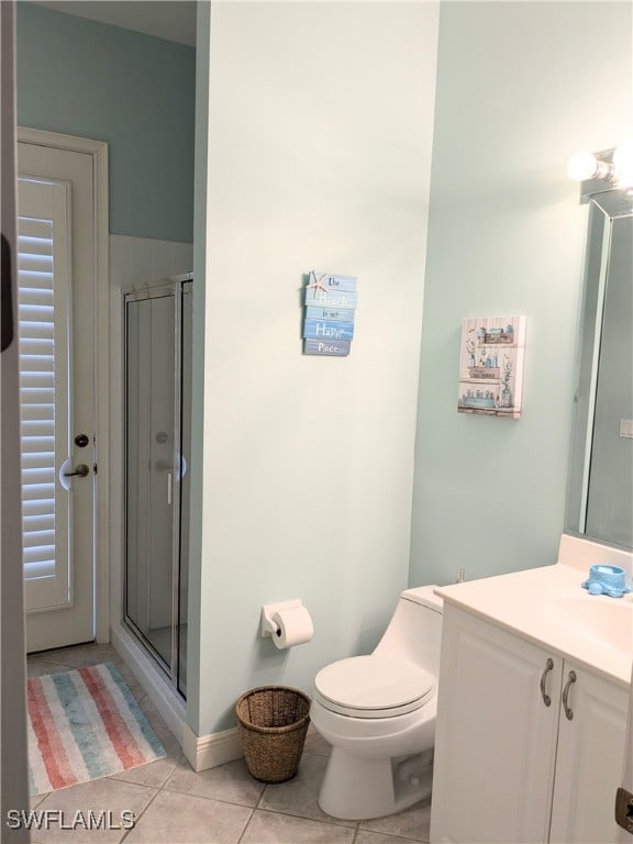 bathroom featuring tile patterned flooring, vanity, toilet, and a shower with shower door