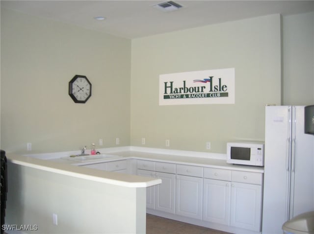 kitchen with white cabinets, sink, light tile patterned floors, white appliances, and kitchen peninsula