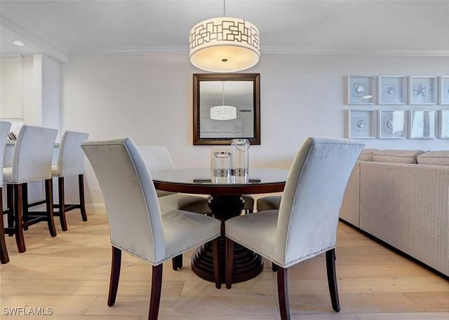 dining space with light wood-type flooring and ornamental molding