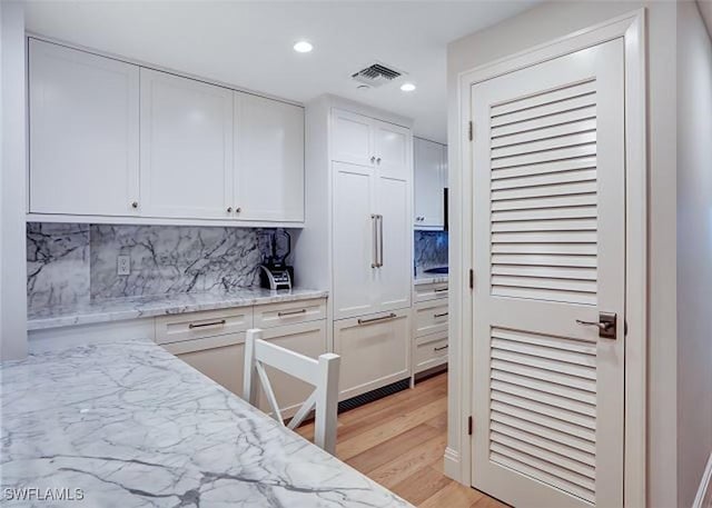 kitchen with decorative backsplash, white cabinets, and light stone counters