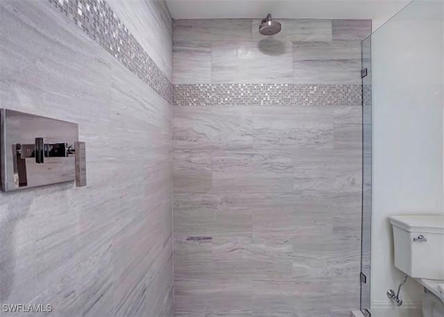 bathroom featuring a shower with shower door and toilet