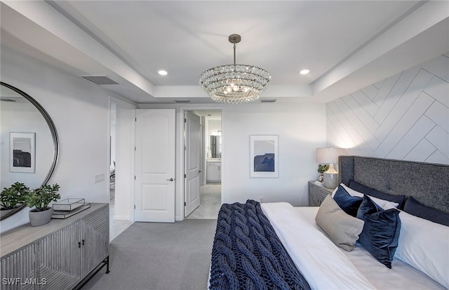 carpeted bedroom featuring ensuite bath, a notable chandelier, and a tray ceiling