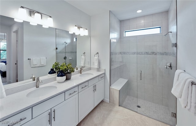 bathroom with vanity, a shower with shower door, a healthy amount of sunlight, and tile patterned flooring