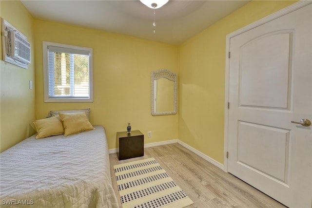 bedroom featuring an AC wall unit, light hardwood / wood-style flooring, and ceiling fan