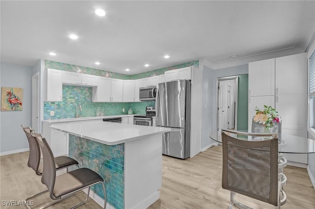 kitchen with appliances with stainless steel finishes, sink, white cabinetry, a breakfast bar, and a kitchen island