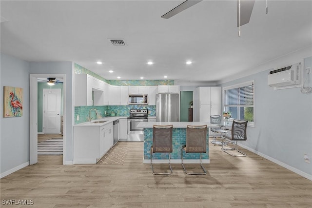 kitchen featuring sink, white cabinetry, a kitchen island, a wall mounted AC, and stainless steel appliances