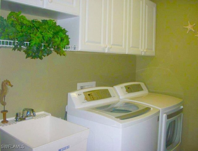 clothes washing area featuring separate washer and dryer, cabinets, and sink