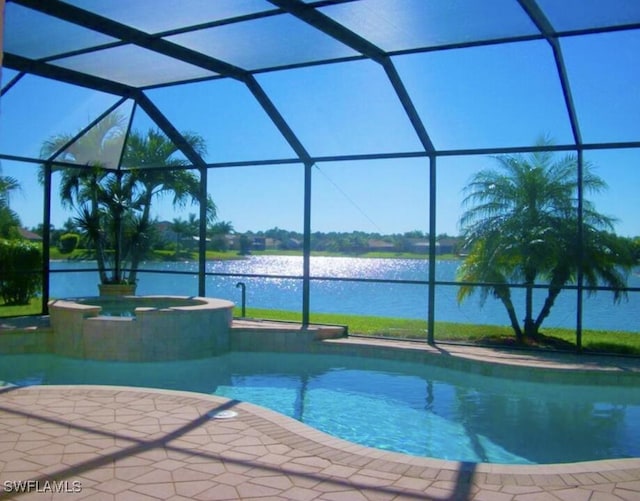 view of pool featuring a patio area, an in ground hot tub, glass enclosure, and a water view