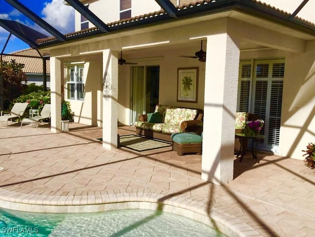 view of patio featuring ceiling fan, glass enclosure, and outdoor lounge area