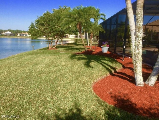 view of yard with a lanai and a water view