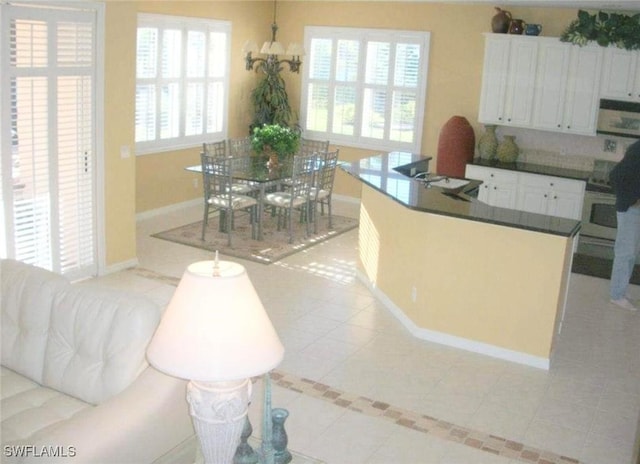 kitchen featuring white cabinets, wall oven, light tile patterned floors, and a chandelier