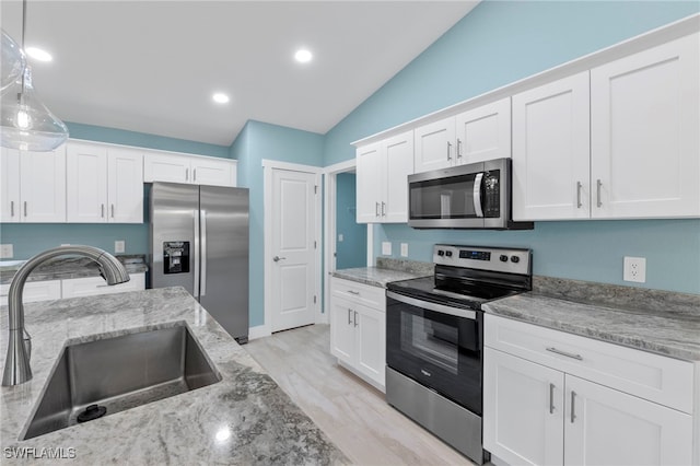 kitchen with white cabinetry, sink, stainless steel appliances, and vaulted ceiling