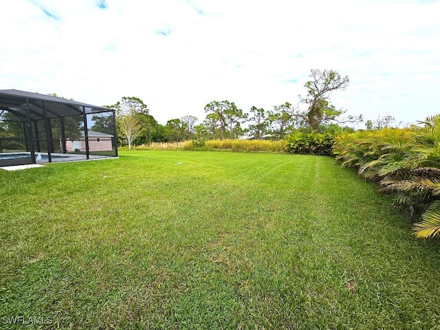 view of yard featuring glass enclosure and a swimming pool