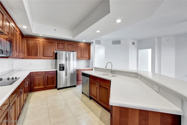 kitchen with sink, black appliances, light tile patterned floors, a raised ceiling, and a kitchen island with sink