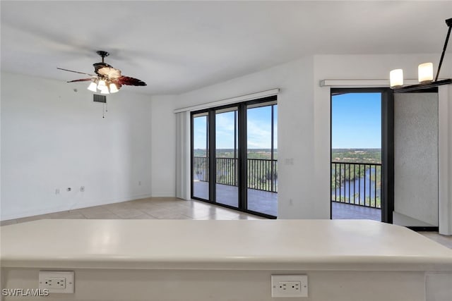 interior space with a water view, light tile patterned floors, and ceiling fan