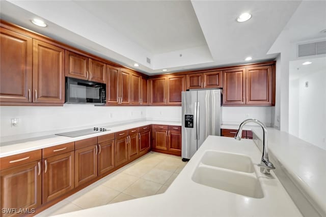 kitchen with light tile patterned floors, sink, black appliances, and a raised ceiling