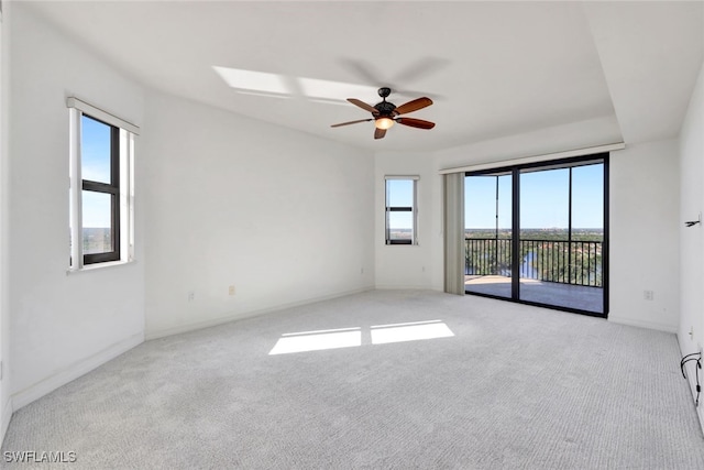 spare room with ceiling fan, plenty of natural light, and light carpet