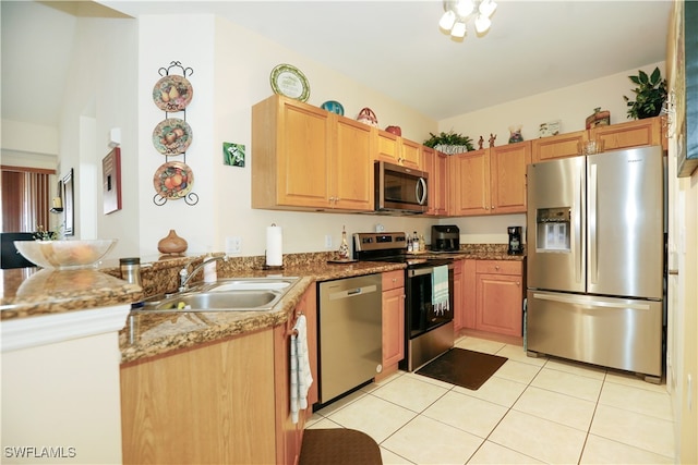 kitchen with sink, kitchen peninsula, stone countertops, light tile patterned floors, and appliances with stainless steel finishes