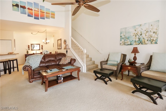 carpeted living room featuring a towering ceiling and ceiling fan with notable chandelier