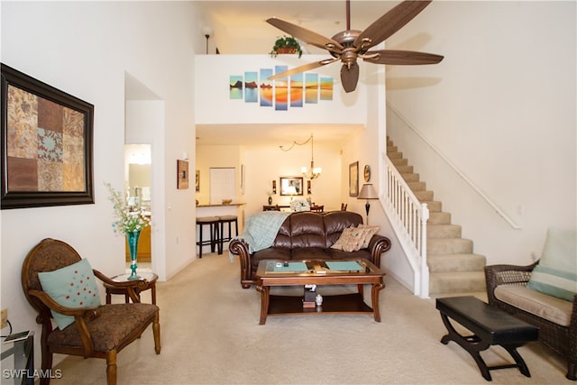 living room featuring light carpet, a towering ceiling, and ceiling fan with notable chandelier