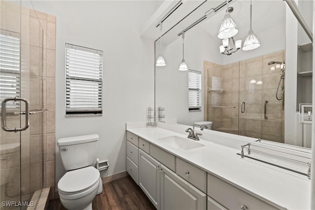 full bath with toilet, a stall shower, vanity, wood finished floors, and baseboards