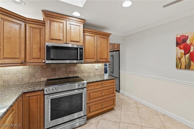 kitchen with ornamental molding, backsplash, high quality appliances, and dark stone countertops