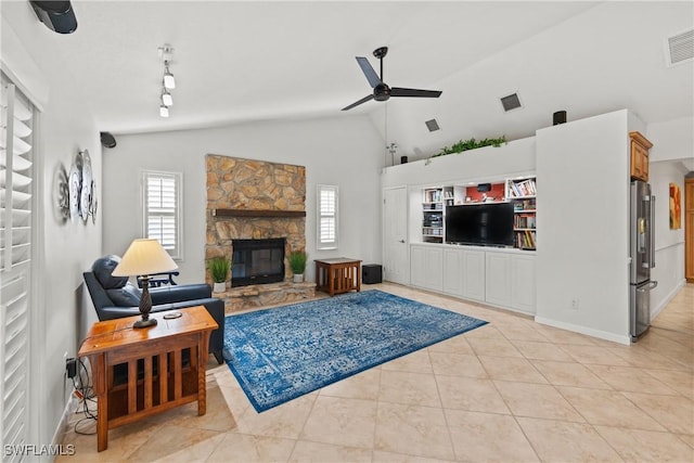 tiled living room featuring a stone fireplace, ceiling fan, and high vaulted ceiling